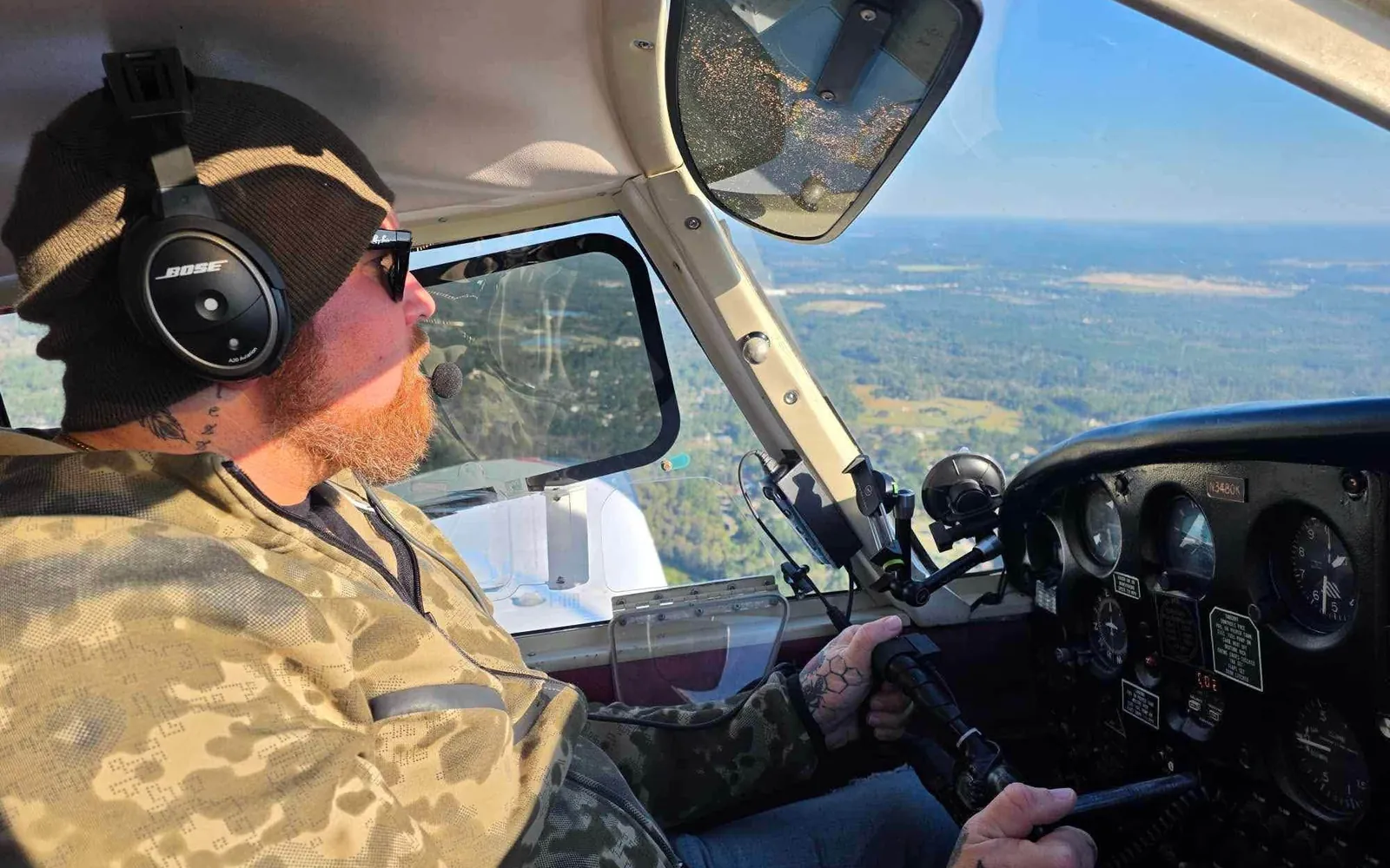 Anthony, a veteran, at the controls of Piper Cherokee N3480K during a VA Ready sponsored discovery flight, wearing a headset, beanie and sunglasses, with the Georgia landscape below